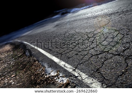 Travel concept. Cracked asphalt and curve road.Road lines