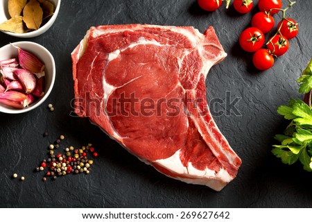 Still life raw thick rib over black background from above