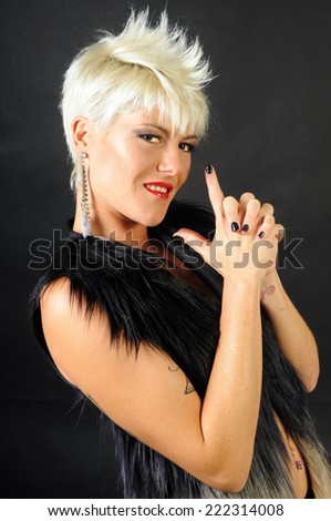 blond trendy short haired woman with crest posing for the camera imitating a pistol with her hands