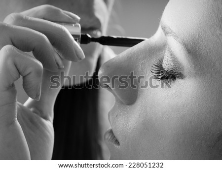 Make up artist drawing an eye line close up in black and white