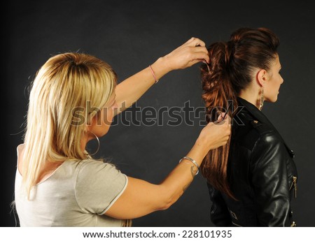 hair stylist making a braid to a Young slim model on black background