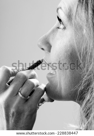 a make up artist hand close up applying lips line with a pencil in black and white