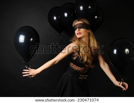 Young beautiful slim girl wearing black lace sensual top and black skirt posing with black balloons on black background
