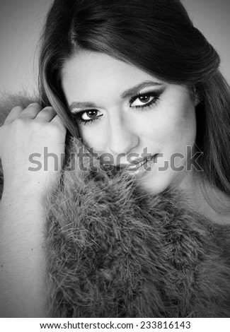 close up black and White portrait of a Young sensual beautiful girl posing with fur coat close to her Young perfect skin