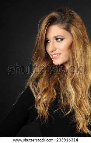 portrait of Young girl with long perfect hair smiling and looking away isolated on black
