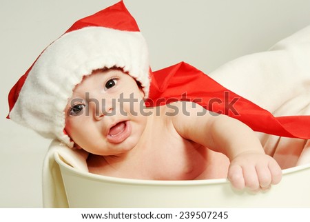 little Amazing baby boy posing in a basket and wearing long red santa hat close up portrait with open mouth