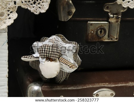 handcrafted woolen sheep decorated with lace on the vintage leather luggage bags with old fashioned locks