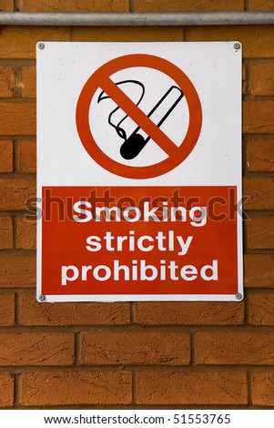 An anti smoking sign that reads \'Smoking Strictly Prohibited\' on a brick wall.