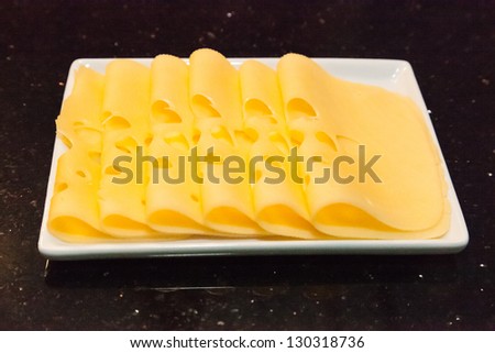 Sliced semi-hard cheese on white rectangle plate.