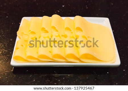 Sliced semi-hard cheese on white rectangle plate.