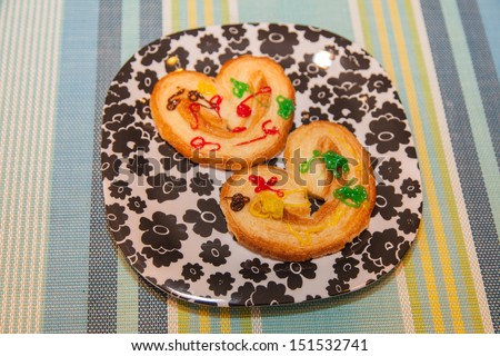 Decorated heart shaped cookies on plastic plate.