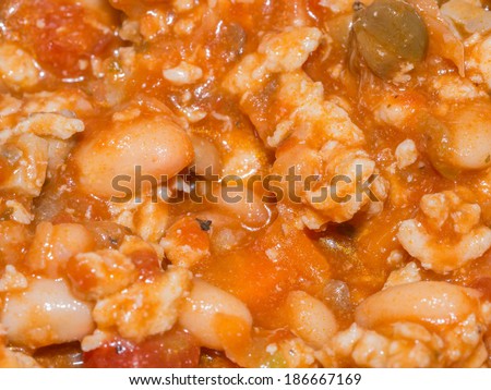 Making one pot stew with a tomato sauce base including ground turkey, chopped onions, chopped carrots and white beans.