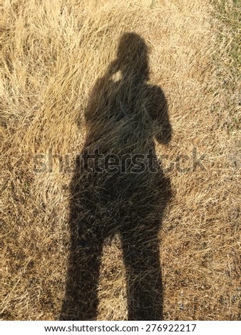 Shadow of a person taking a picture on the ground.