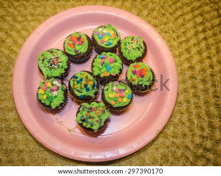 Mini cupcakes with green frosting on large round plate.