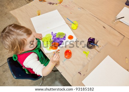 Cute little baby girl having fun painting at art class
