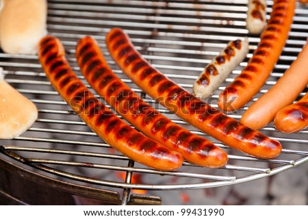 Grilling hot dogs with buns on a garden grill.