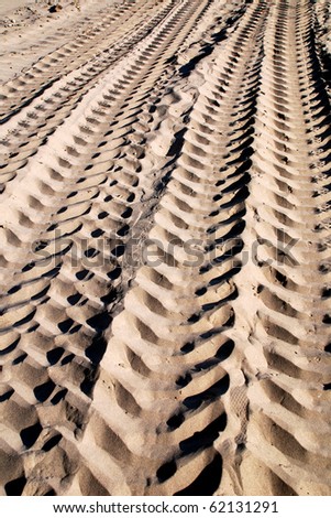 Sand tracks Sand tracks Dramatic sand tracks making a detailed texture with highlights and shadows of a large tire tracks in sand. Tan tones of natural color sand in the fresh tracks on the beach.
