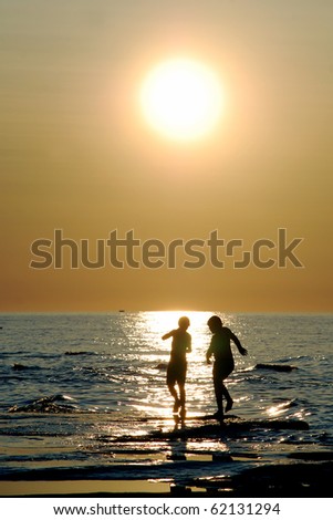 Kids dancing in reflection of sunlight. two silhouetted kids dance in sparkling \
