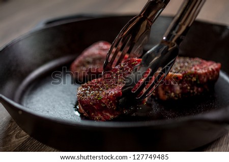 Chef is placing tenderloin steaks with kitchen tongs