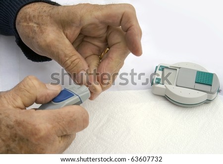 Checking sugar levels: closeup of diabetic senior male\'s hands while he is checking his sugar levels.