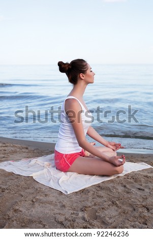 Young beautiful woman doing yoga near the sea alone