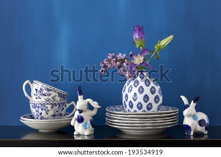 Still life with blue and white dishes, porcelain bunnies and flowers in a little vase