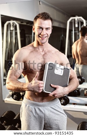 Muscular young man with weight scale