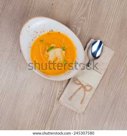 Cream of pumpkin soup beside pouch with spoon