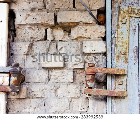 Brick wall with part of door and door hinges.