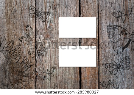 Horizontal business card mockup over natural wood deck table background. Card is 50x90mm. Wood deck have doodle pictures with sunflowers and butterflies.