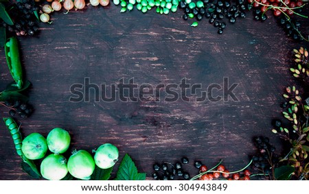 Template frame with berries, leaves, black currant, red currant, green peas, barberry and apple on vintage wood table