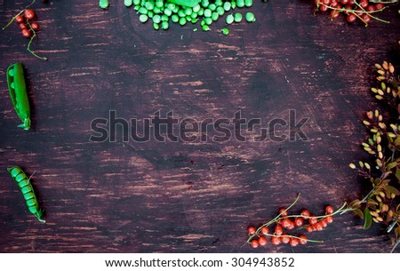 Template frame with berries, leaves, red currant, green peas, barberry and apple on vintage wood table