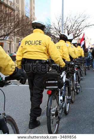 power riot police lined up and moving in on a crowd of anti war protestors with cycles bicycles