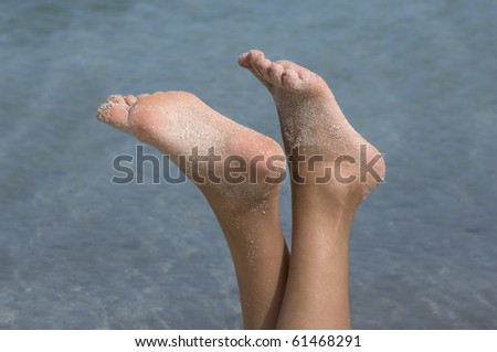 Female feet in the air on the beach