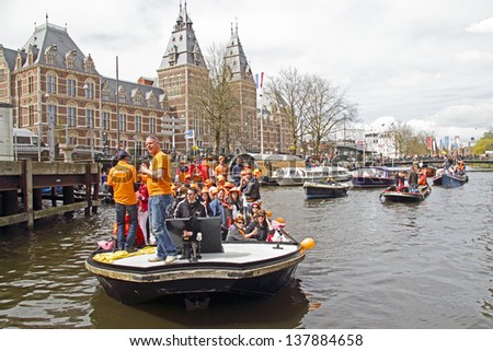 AMSTERDAM, NETHERLANDS - APRIL 30: People in orange celebrating in Amsterdam on the canals during the coronation of the new king Willem Alexander from the Netherlands on 30 april 2013