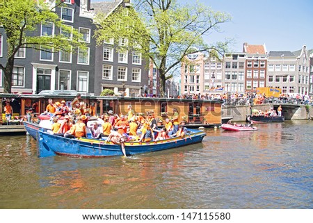 AMSTERDAM - APRIL 30: Amsterdam canals full of boats and people in orange during the celebration of queensday on April 30, 2013 in Amsterdam, The Netherlands
