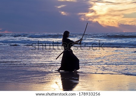 Young samurai women with Japanese sword(Katana) at sunset on the beach