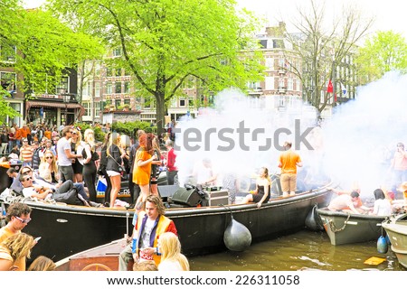 AMSTERDAM - APRIL 26: Amsterdam canals full of boats and people in orange during the celebration of kings day on April 26, 2014 in Amsterdam, The Netherlands