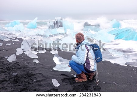 Tourist at ice rocks on the black sand beach in Iceland