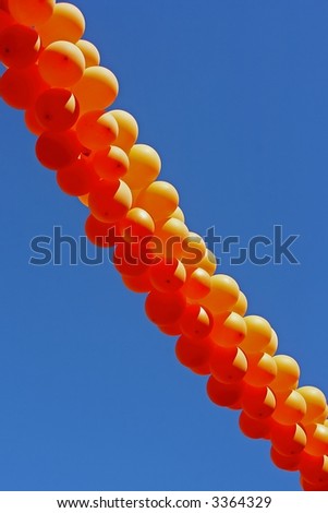 Orange party balloons against a blue sky