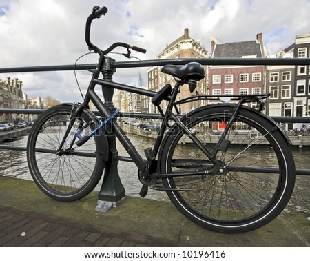 Black bike chained at the bridge from an Amsterdam canal in the Netherlands