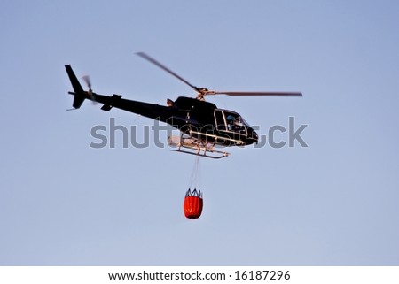Fire fighting helicopter with waterbag on his way to combat the forest fire