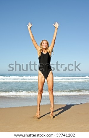 Young beautiful blonde woman making a jump out of joy at the beach
