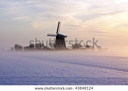 Traditional windmill at twilight with fog and snow in winter in the Netherlands