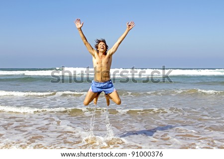 Young happy guy jumping out of the water at the atlantic ocean in Portugal