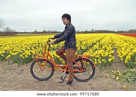 Tourist on a orange bike at the flower fields in the countryside from the Netherlands