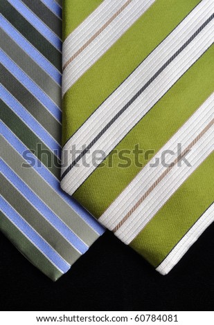 Two ties in green, blue and white tones on a black background.