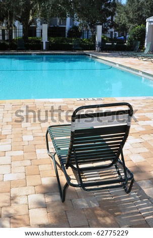 Green pool chair in front of a swimming pool, vertical view