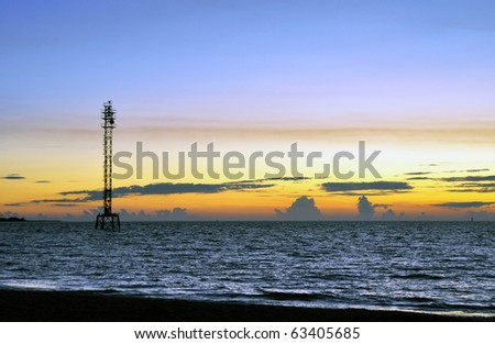 A metal tower in middle of the gulf coast ocean at sunset
