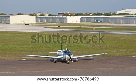 A white and blue small propeller airplane with one of it\'s doors opened, at an airport hangar in St. Petersburg, FL.